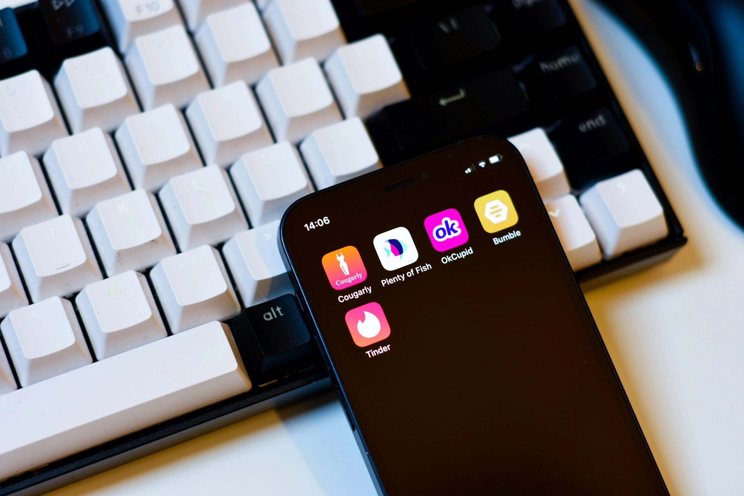Ecrã de telemóvel com aplicações de encontros como Tinder, Bumble e OkCupid sobre um teclado branco